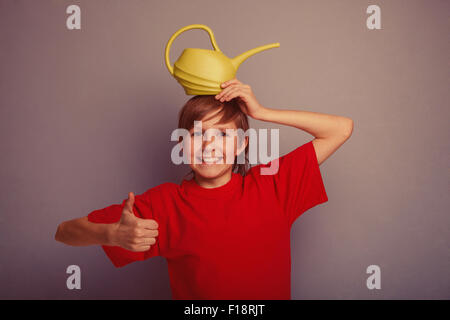 Adolescents de douze ans en chemise rouge holding watering can ret Banque D'Images