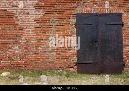 Une vieille porte métallique dans un mur de brique rouge, tourné en Bodie, USA. Banque D'Images