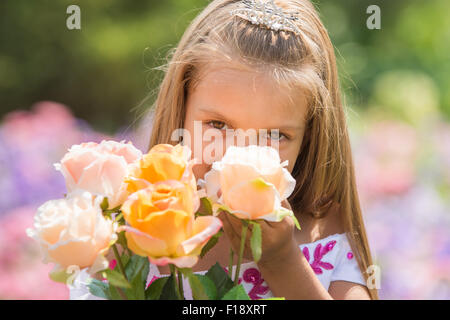 Heureux fillette de six ans dans un cadre de soirée robe rose marche à travers le jardin vert Banque D'Images