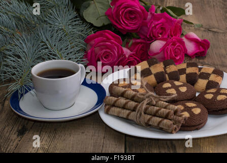 Tasse de café, roses et la plaque avec des cookies sur une table Banque D'Images