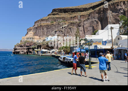 Les touristes dans des vêtements d'été debout sur le quai du vieux port de Santorin, en Grèce. Banque D'Images