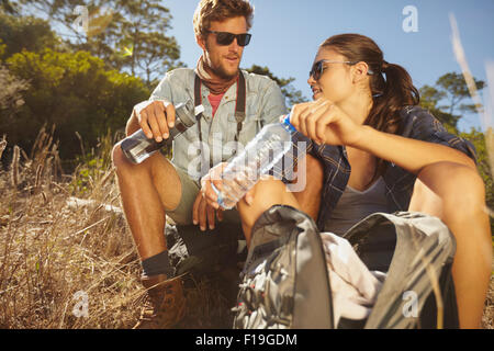 Jeune couple en faisant une pause sur une randonnée. Man and Woman eau potable lorsqu'ils randonnées Banque D'Images