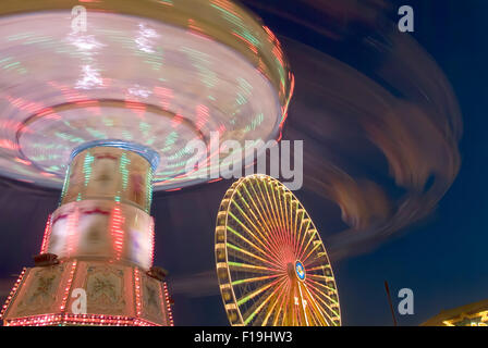 Fête foraine avec roue géante et merry go round in motion soir lumière allemagne europe Banque D'Images