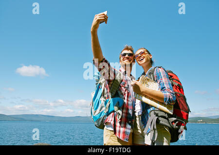 Joyeux randonneurs de décisions lors d'un voyage selfies contre le ciel bleu Banque D'Images