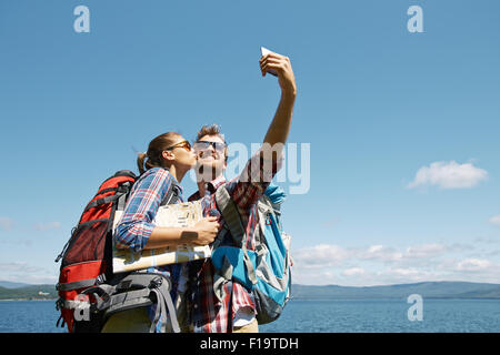 Homme heureux de faire lors d'un voyage tout en selfies embrasser sa petite amie Banque D'Images