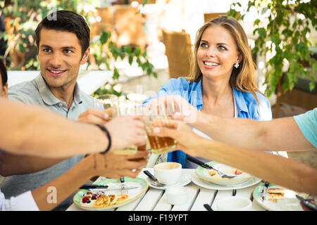 Un groupe d'amis autour de la table toast à dîner dans le restaurant de plein air Banque D'Images