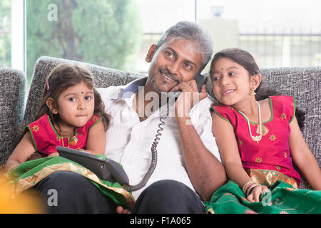 Mari faire un appel à la femme tout en prenant soin des enfants à la maison. Famille indienne asiatique à la maison. Banque D'Images