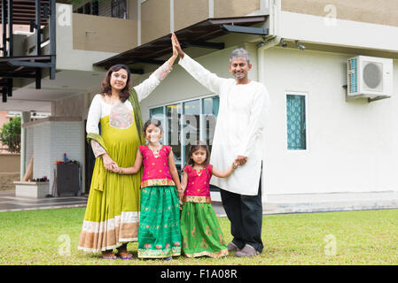 Les parents formant toit de maison au-dessus des enfants. Belle asiatique Indian Family portrait souriant et debout devant leur nouveau h Banque D'Images