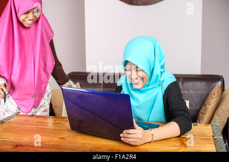 Deux jeunes femmes musulmanes de faire une discussion de groupe en utilisant un ordinateur portable Banque D'Images