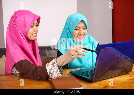 Deux jeunes femmes musulmanes de faire une discussion de groupe en utilisant un ordinateur portable Banque D'Images