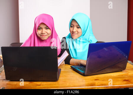 Deux jeunes femmes musulmanes de faire une discussion de groupe en utilisant un ordinateur portable Banque D'Images