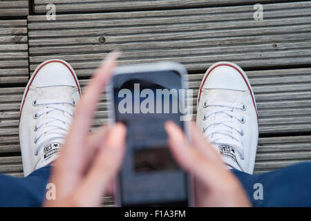 Un des modèles d'adolescent vue aérienne de son iphone, à la recherche jusqu'à ses pieds. Banque D'Images