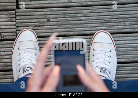 Un des modèles d'adolescent vue aérienne de son iphone, à la recherche jusqu'à ses pieds. Banque D'Images