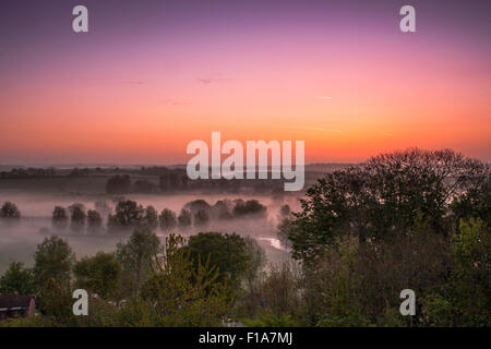 La brume tôt le matin enveloppe les arbres et les collines au lever du soleil dans la campagne du Dorset, Royaume-Uni Banque D'Images