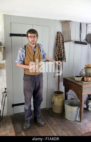 Old Bethpage, New York, USA. Août 30, 2015. Matt, un membre du personnel saisonnier portant des vêtements américains de style traditionnel, montre une grande baratte pendant une visite de la maison Powell pendant l'ancien temps Music Week-end à Old Bethpage Village Restauration. La maison a été construite en 1750 et est restauré à sa taille, et élargi 1855 est le seul immeuble de standing sur son emplacement d'origine dans le village. Credit : Ann Parry/ZUMA/Alamy Fil Live News Banque D'Images