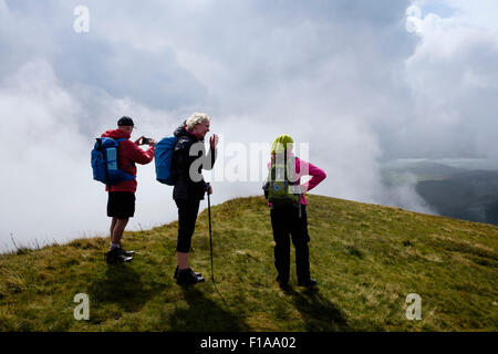 Trois randonneurs randonnée sur la montagne à l'ouest de l'Ddysgl Bostn le long de la crête de Nantlle de nuages bas dans la région de montagnes de Snowdonia, Pays de Galles, Royaume-Uni Banque D'Images