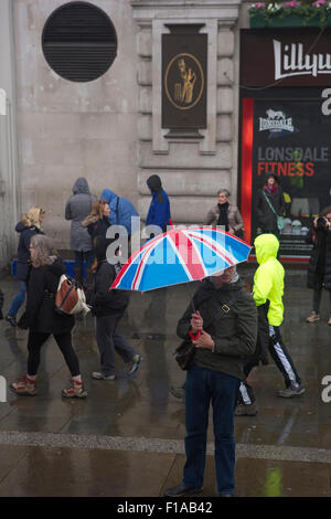 Un homme tenant un parapluie montrant le drapeau britannique (Union Jack) dans une rue pluie à Londres Banque D'Images