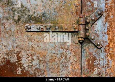 Milieux et de textures : rusty metal surface de la porte avec charnières rivetées, industriel abstract Banque D'Images