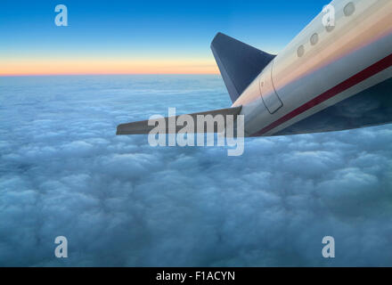 Une compagnie aérienne commerciale avion à réaction volant au-dessus des nuages à coucher du soleil Banque D'Images