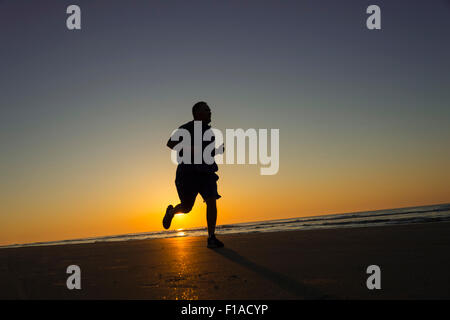 Fat Man Running On Beach At Sunrise Banque D'Images