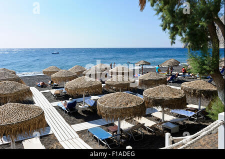 Des parasols de paille sur la plage de Kamari, Santorini, Grèce. Banque D'Images