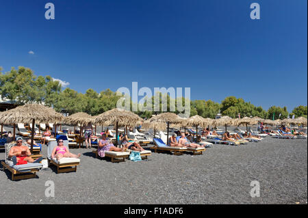 Les touristes à prendre le soleil sur la plage de Kamari, Santorini, Grèce. Banque D'Images