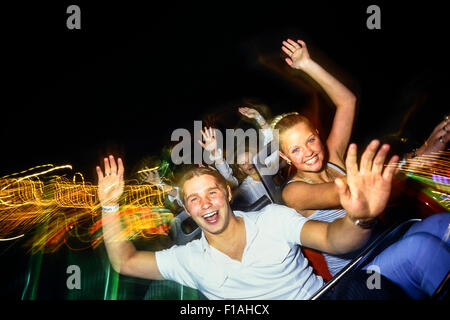 Un jeune couple appréciant un roller coaster ride de nuit à l'île de l'aventure. Southend-on-Sea. L'Essex. UK Banque D'Images