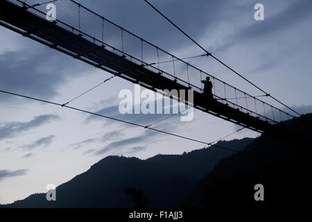 Une personne marchant à travers la passerelle sur la rivière Trishuli à Kurintar, Napal Banque D'Images