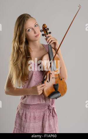 Belle Jeune femme debout tenant son violon musicien bercé dans son bras en regardant la caméra avec un sourire, sur une Banque D'Images