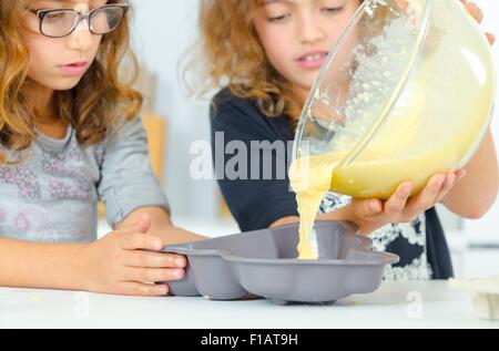 Verser le mélange à gâteau avec deux filles Banque D'Images