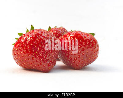 Trois fraises rouges mûres fraîches, isolé sur blanc avec ombre douce. Banque D'Images