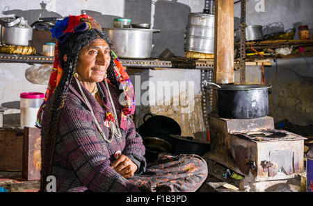 Une femme de la tribu brokpa, travailler dans la cuisine, vêtu de sa robe traditionnelle avec la fleur typique couvre-chef, Dah Hanu Banque D'Images