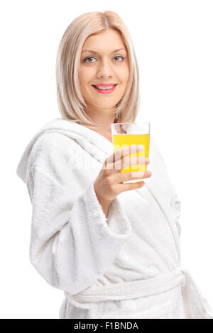 Shot verticale d'une jeune fille enjouée dans un peignoir blanc tenant un jus d'orange et regardant la caméra Banque D'Images