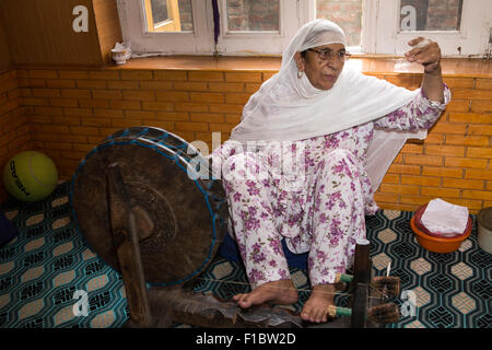 L'Inde, le Jammu-et-Cachemire, Srinagar, vieille femme Cachemire pashmina fine spinning thread sur roue en chambre Banque D'Images