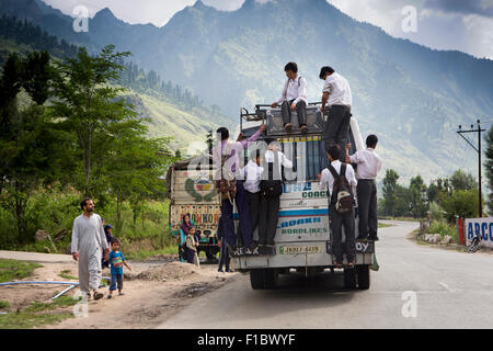 L'Inde, le Jammu-et-Cachemire, Srinagar à Leh Highway, à l'école les enfants s'accrocher à l'arrière du bus surchargé Banque D'Images