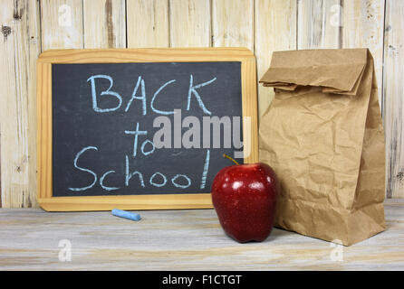 Retour à l'école Inscription sur tableau noir à la pomme et sac en papier brun sur blanchir le bois. Banque D'Images