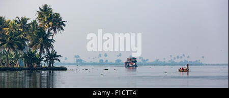 Les eaux placides tôt le matin du Lac Vembanad , Kumarakom dans les Backwaters du Kerala. Des bateaux et des palmiers visible à distance Banque D'Images