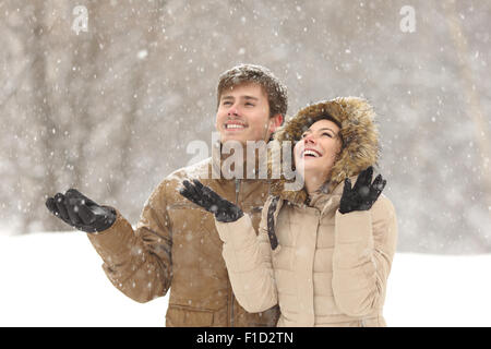 Drôle de couple regardant la neige en hiver durant une chute de neige en vacances Banque D'Images