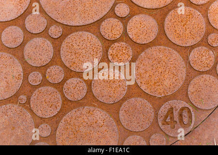 Un manteau de trou d'homme en fonte islandaise rouillée avec un motif abstrait dans des cercles de différentes tailles. Seyðisfjörður, Islande Banque D'Images