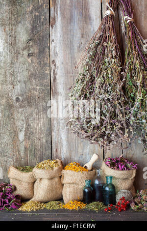 Herbes de guérison dans des sacs de jute près de mur en bois rustique, de médecine de fines herbes. Banque D'Images