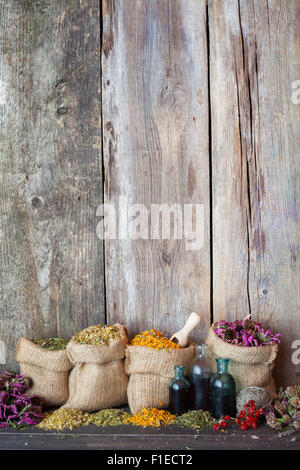 Herbes de guérison dans des sacs de jute sur le vieux fond de bois, de plantes médicinales. Banque D'Images