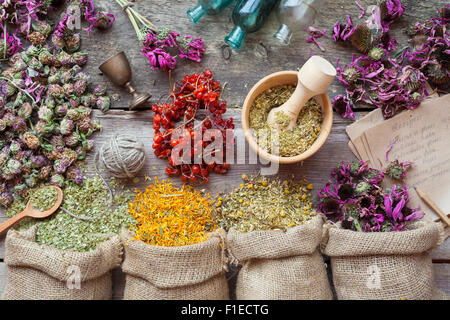 Herbes de guérison dans des sacs de jute, mortier en bois, petites bouteilles sur la vieille table en bois, la médecine de fines herbes. Vue d'en haut. Banque D'Images