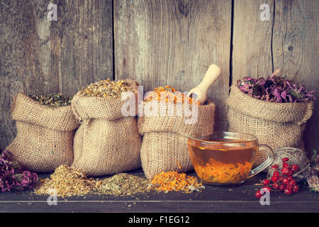 Herbes de guérison dans des sacs de jute et tasse de thé, de saine phytothérapie.de style rétro. Banque D'Images