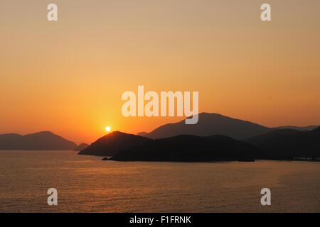 Image d'un coucher du soleil doré avec des montagnes au loin sur la mer Banque D'Images