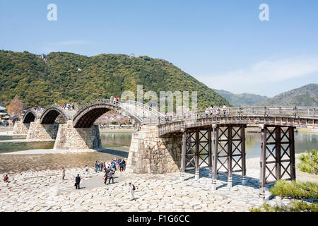 Iwakuni, Japon. Le multi-arquée pont en bois Kintaikyo, célèbre site touristique, enjambant la rivière Nishiki-gawa, avec château Iwakuni en montagne. Banque D'Images