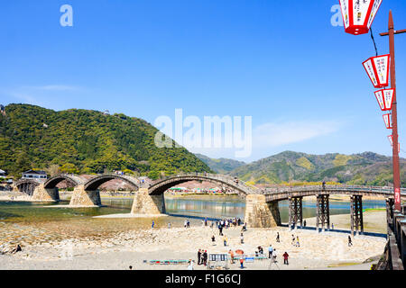 Iwakuni, Japon. Le multi-arquée pont en bois Kintaikyo, célèbre site touristique, enjambant la rivière Nishiki-gawa, avec château Iwakuni en montagne. Banque D'Images