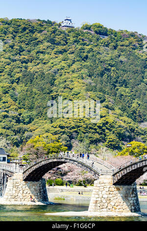 Iwakuni, Japon. Le multi-arquée pont en bois Kintaikyo, célèbre site touristique, enjambant la rivière Nishiki-gawa, avec château Iwakuni en montagne. Banque D'Images