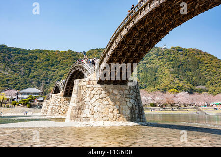 Iwakuni, Japon. Le multi-arquée pont en bois Kintaikyo, célèbre site touristique, enjambant la rivière Nishiki-gawa, avec château Iwakuni en montagne. Banque D'Images