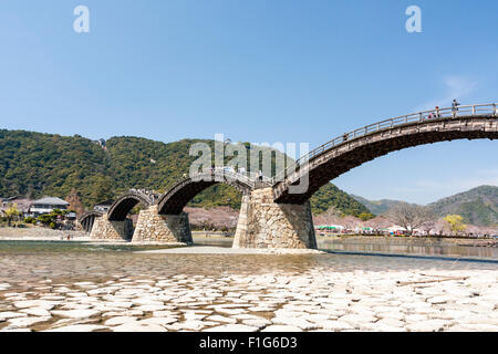 Iwakuni, Japon. Le multi-arquée pont en bois Kintaikyo, célèbre site touristique, enjambant la rivière Nishiki-gawa, avec château Iwakuni en montagne. Banque D'Images