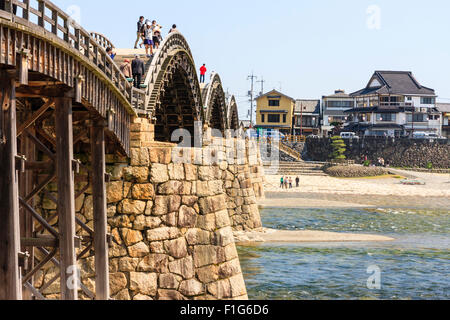 Iwakuni, Japon. Le multi-arquée pont Kintaikyo en bois, avec des personnes qui traversent, célèbre site touristique et monument, enjambant la rivière Nishiki-gawa. Banque D'Images